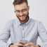 Happy fashionable male student sits on work place, prepares for classes, holds mobile phone, uses photo editing applications, posts new pictures via social networks, isolated over white background - Газета Магаданская правда